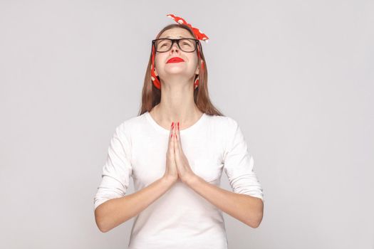 Oh my God please help me. portrait of beautiful emotional young woman in white t-shirt with freckles, black glasses, red lips and head band. indoor studio shot, isolated on light gray background.