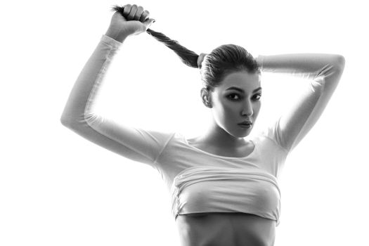 Beautiful young chinese european sexy fashion model posing in white t-shirt and undressing her white transparent shirt and looking at camera with passion. black and white photography, studio shot.