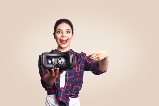 Young beautiful woman in casual style with virtual reality headset on beige background. studio shot. .