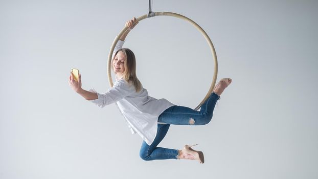 Caucasian woman gymnast on an aerial hoop takes a selfie on a smartphone