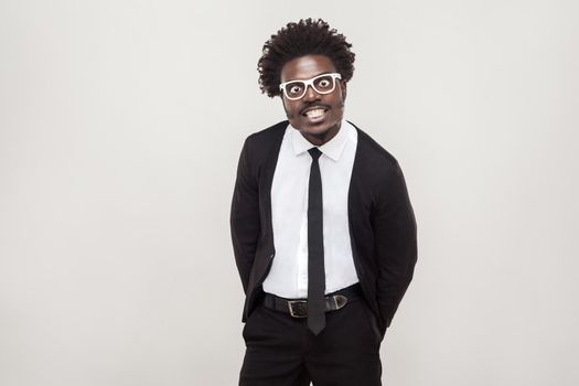 Idiotic afro man in white glasses grimacing at camera. Studio shot, gray background