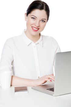 Portrait of happy successful attractive brunette businesswoman in white shirt sitting with laptop, looking with toothy smile satisfied face expression. indoor studio shot, isolated in white background