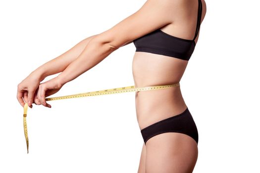 Slim fit happy young woman with measure tape measuring her waist with black underwear, isolated on white background. studio shot.