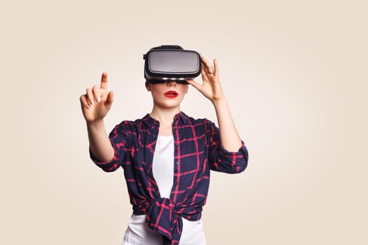 Young beautiful woman in casual style with virtual reality headset on beige background. studio shot. .