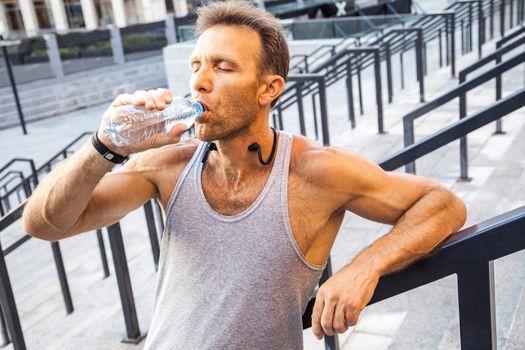 Thirsty sportsman take a rest and drinking water after running. fitness, sport, exercising and people healthy lifestyle concept.