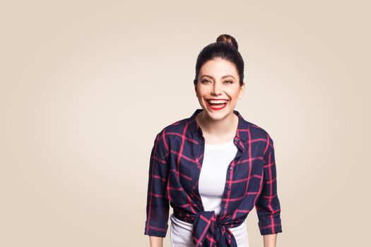 Portrait of beautiful laughing happy girl in casual style looking at camera and laughing. studio shot on beige background.