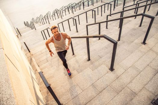 Fitness, sport, exercising and people healthy lifestyle concept. Man running upstairs in the city.