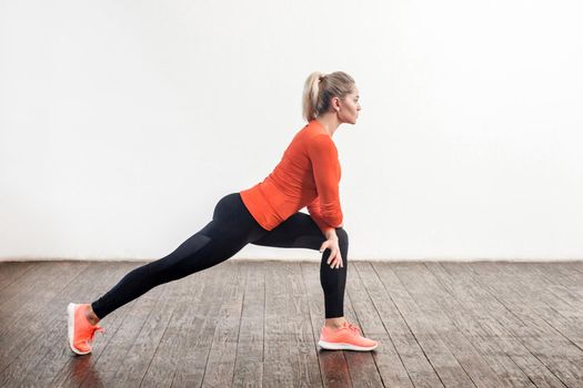 Slim athletic beautiful woman in tight sportswear doing stretching legs workouts for better flexibility, lower-body exercise. Health care, sports activity at home. indoor studio shot, side view