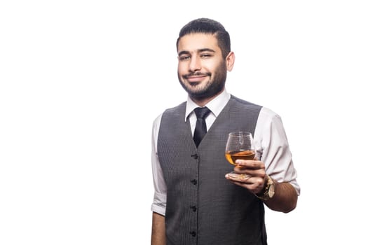 Handsome bearded businessman holding a glass of whiskey. smiling and looking at camera. studio shot, isolated on white background.