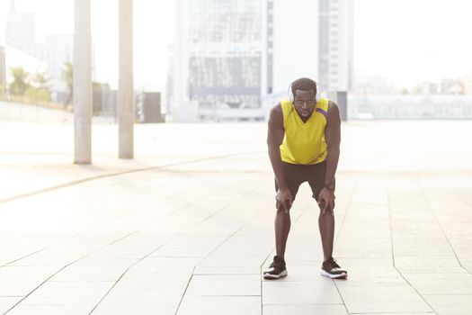 Finally finish. Sporty african man resting after workout exercise. Outdoor photo, blurred background