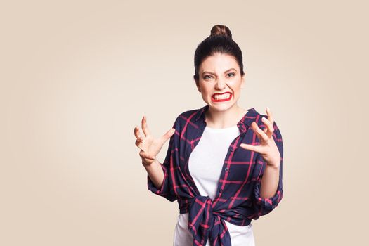 Portrait of stressed and annoyed young casual styled caucasian woman with hair bun holding hands in mad furious gesture, screaming with ragea nd anger. Negative human emotions, facial expressions