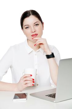 Portrait of happy attractive brunette businesswoman in white shirt sitting, holding cup of drink, touching her chin and looking at camera smiling. indoor studio shot, isolated in white background.