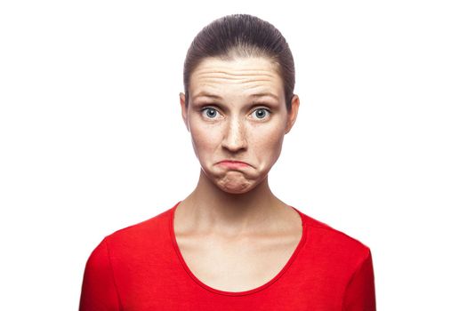 I don't know. portrait of funny confused woman in red t-shirt with freckles. looking at camera, studio shot. isolated on white background.