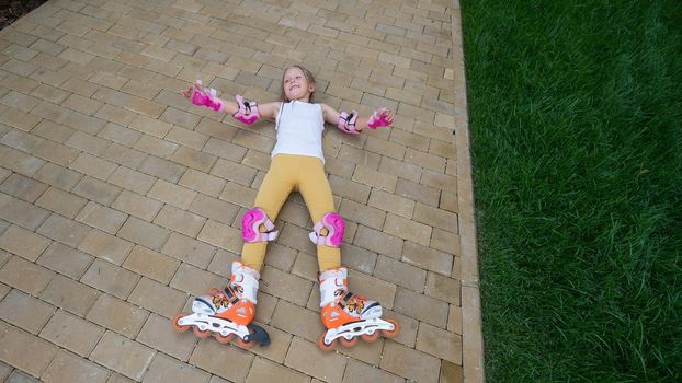 Little girl learns to roller skate and falls. View from above.