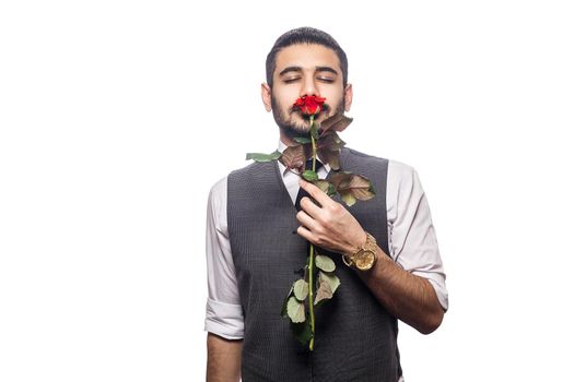 Handsome romantic happy man with rose flower. studio shot. isolated on white background. holding and smelling rose with closed eyes..