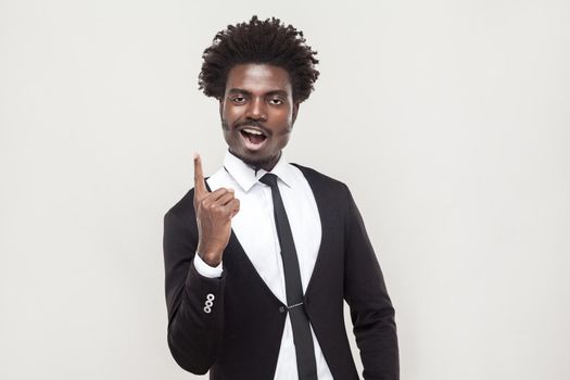 Happiness afro man looking at camera with idea finger. Studio shot, gray background