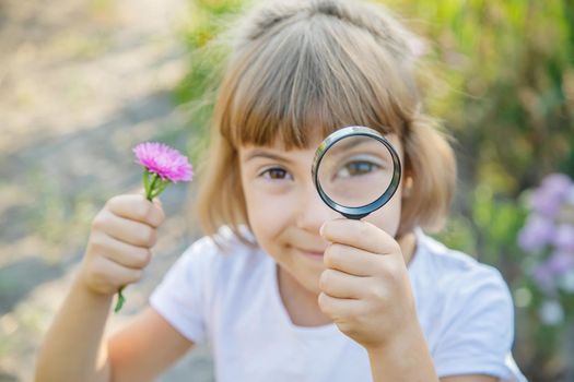 Child with a magnifying glass in his hands. Selective focus.