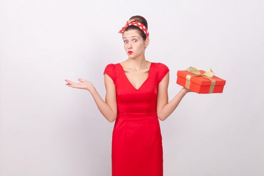 Confused, puzzled cute woman holding box, say don't know. Indoor, studio shot, isolated on gray background