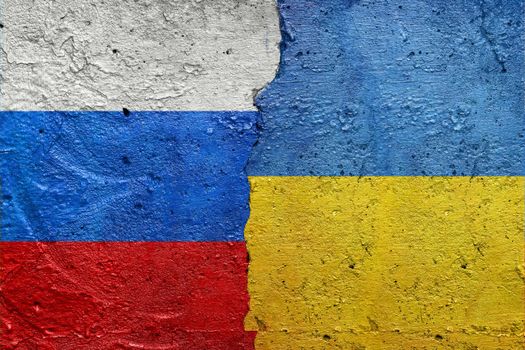 Russia vs Ukraine - Cracked concrete wall painted with a Ukrainian flag on the left and a Russian flag on the right