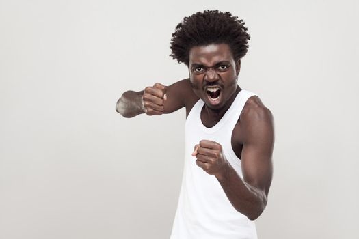 Dangerous fighter. Afro man ready to fight. Studio shot. Gray background