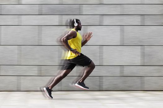 Profile side view of man runner with muscular body in tracksuit jogging against gray wall