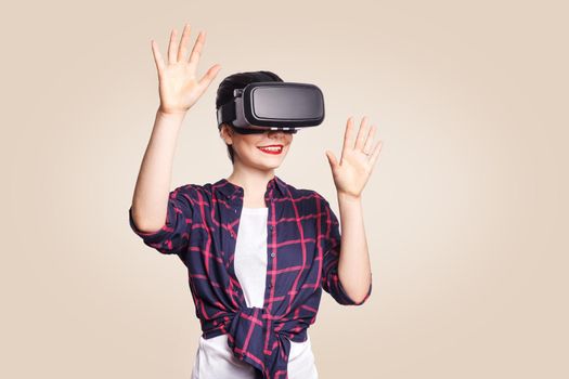 Young beautiful woman in casual style with virtual reality headset on beige background. studio shot. .