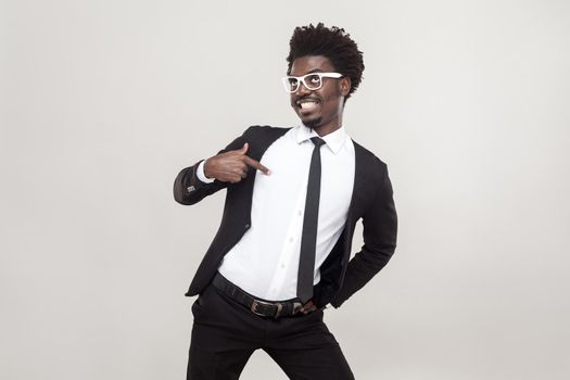 Well dressed proud man pointing finger himself. Studio shot, gray background