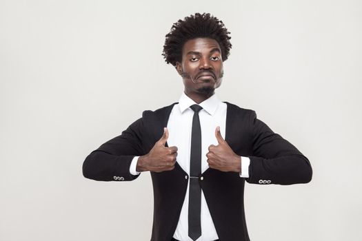 Success businessman looking at camera and thumbs up. Studio shot, gray background