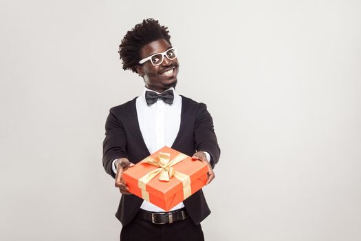 Romantic african businessman showing gift box for valentines day. Studio shot.