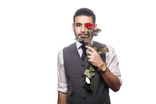 Handsome romantic happy man with rose flower. studio shot. isolated on white background. holding flower in front of his eyes and looking at camera and smiling...