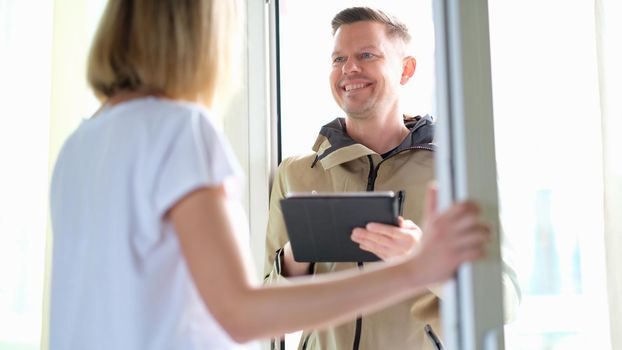 Male courier delivering package and holding tablet with data. Parcel delivery service concept