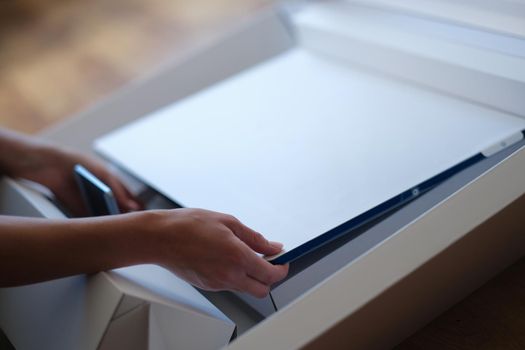 Tbilisi, Georgia - May 25, 2022: Woman removes white protective film from New iMac monitor. iMac Mi series high quality personal monitors concept