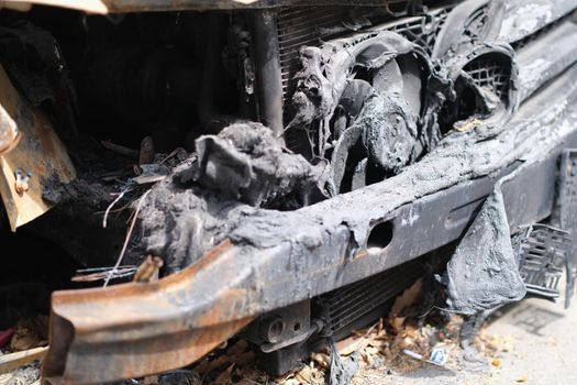 Abandoned burnt car on road after terrorist attack. Car arson and car insurance