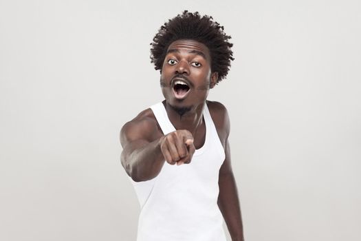 Hey you! No fair! Man pointing finger at camera. Focus on face. Studio shot. Gray background