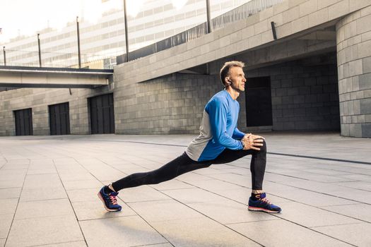 Handsome athlete man in black blue sport uniform stretching body, warming up and get ready for jogging.