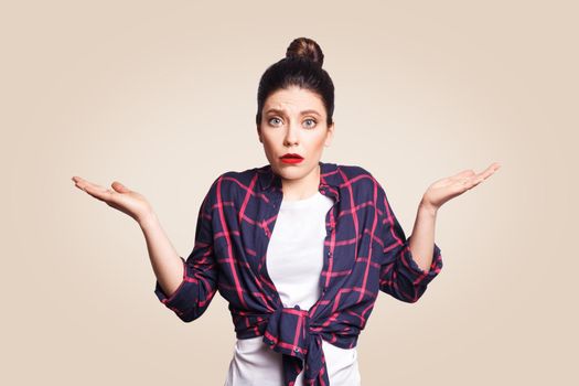 Portrait of young shocked brunette woman with casual style looking desperate or panic, keeping mouth open and making helpless gesture with her hands, doesn't know what to do.