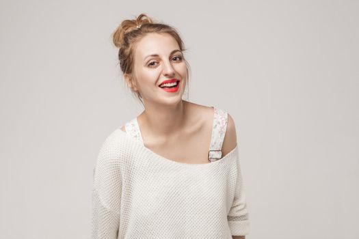 Laughing woman looking at camera and toothy smile. Studio shot, gray background