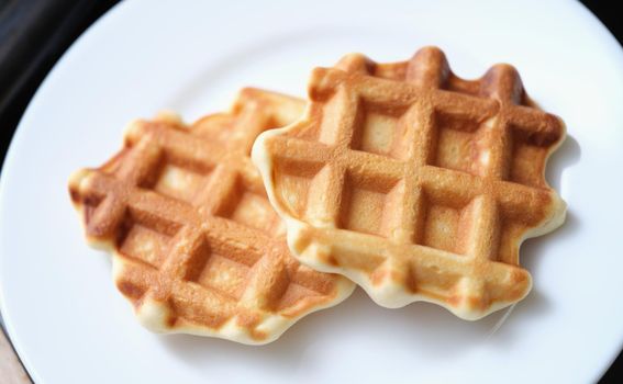 Fresh delicious homemade waffles on white plate. Delicious breakfast concept