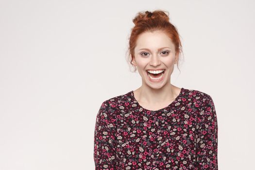 The attractive redhead woman with perfect clean skin smiling at camera with happy and joyful. Isolated studio shot on gray background.