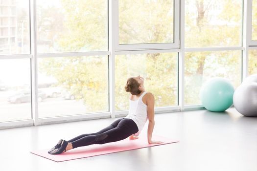 Woman doing yoga, cobra pose, Bhujaṅgāsana posture. Studio shot