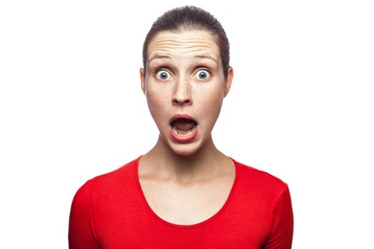 Portrait of happy surprised woman in red t-shirt with freckles. looking at camera excited with big eyes, studio shot. isolated on white background.