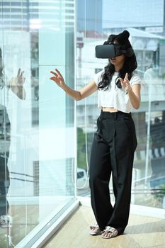 Excited young businesswoman wearing virtual reality headset and interacts with cyberspace. Connection, technology, new generation, progress concept.
