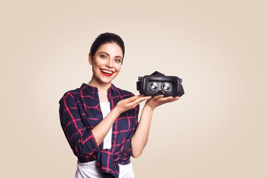 Young beautiful woman in casual style with virtual reality headset on beige background. studio shot. .