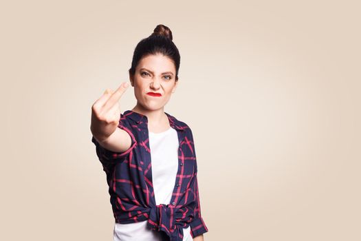 Middle finger sign. Unhappy angry young woman showing middle finger with unsatisfied face. studio shot on beige background. focus on face.