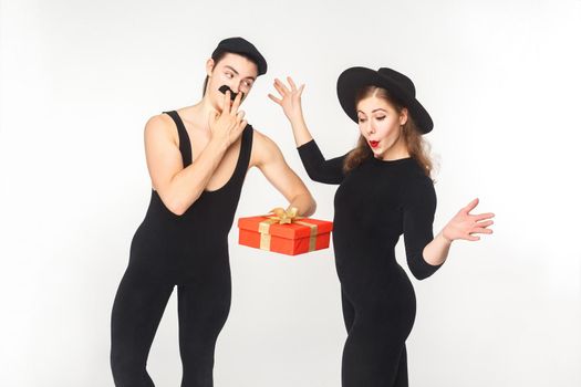 Man with fake mustache present gift box shocked woman. Studio shot, isolated on white background