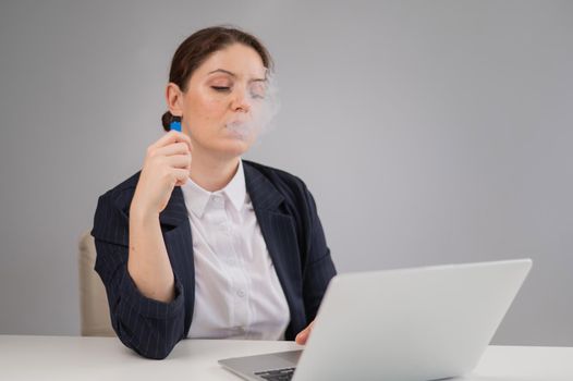 Business woman smoking a disposable vape while sitting at her desk