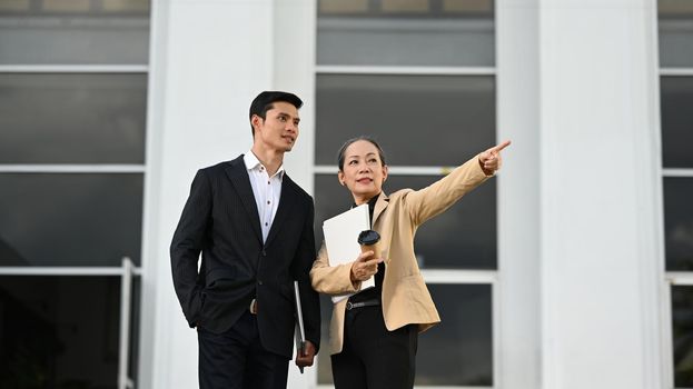 Shot of two businesspeople having a discussion while standing in front of modern offices building.