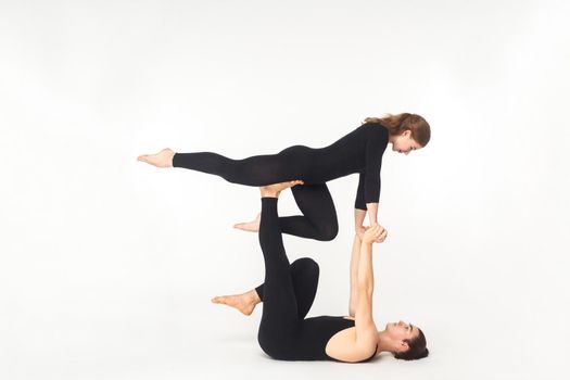 Young man holding woman legs, balancing. Hard circus pose. Studio shot, isolated on white background