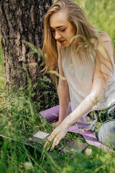 girl sits outdoors and works at a laptop. freelance. selfeducation. the concept of remote learning and outdoor work