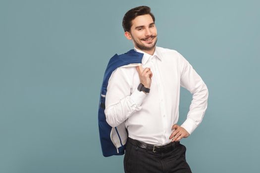 Closeup portrait of success boss, toothy smiling of handsome bearded businessman in white shirt holding his blue jacket, with smart watch. Indoor studio shot, isolated on light blue background